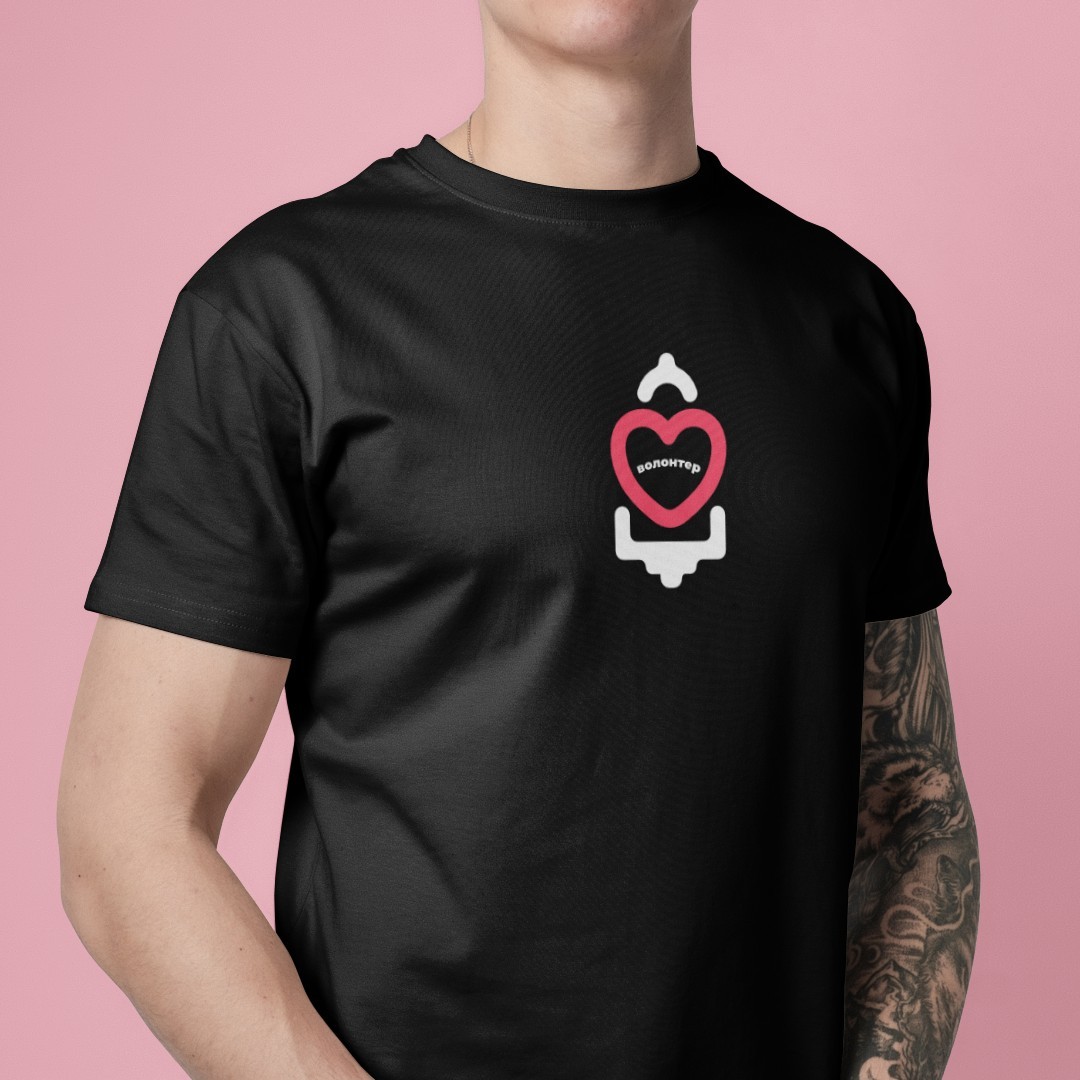 A man wearing a t-shirt with the brand logo. The logo is white but the heart inside the logo is pink.